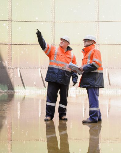 Caucasian technicians examining fuel storage tank